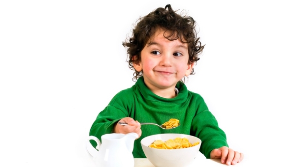 young boy eating cornflakes isolated on white